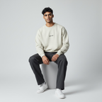Male model wearing the organic natural crewneck whilst sitting on a stool in a photography studio