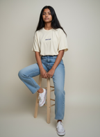 Female model wearing natural raw tshirt whilst eated on a stool