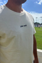 Close up of marine blue embroidered Pier End logo on undyed cotton