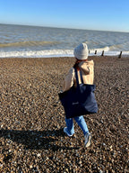 Navy canvas tote carried over the shoulder at the coast