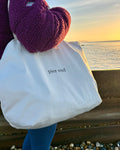Natural canvas tote carried over the shoulder at the beach at sunrise