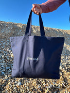 Extra large navy canvas tote bag with bone Pier End print, front view, on the beach