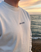 Close up of marine blue embroidered Pier End logo on undyed cotton